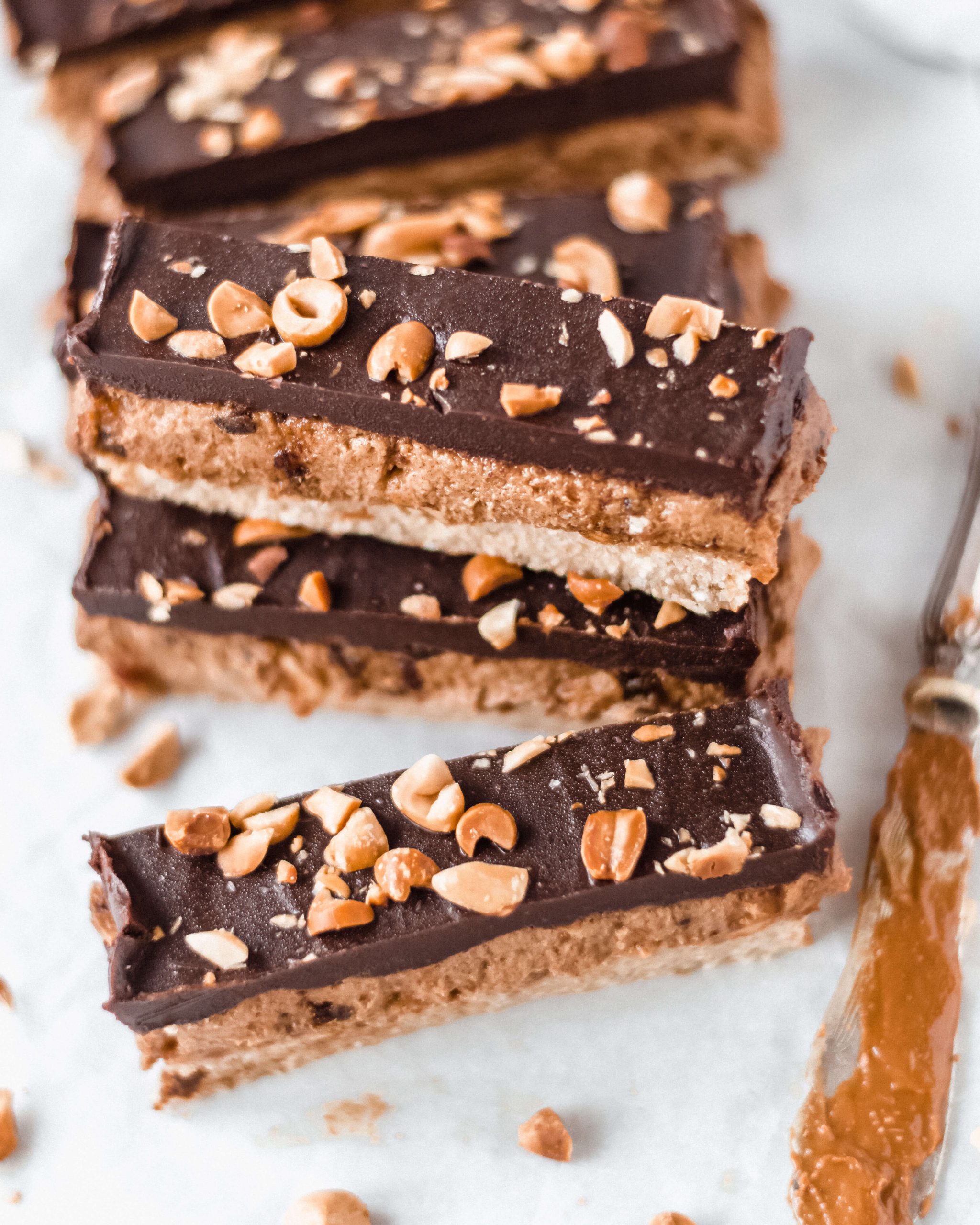 Close up view of peanut and caramel bars with nuts, knife on the side 