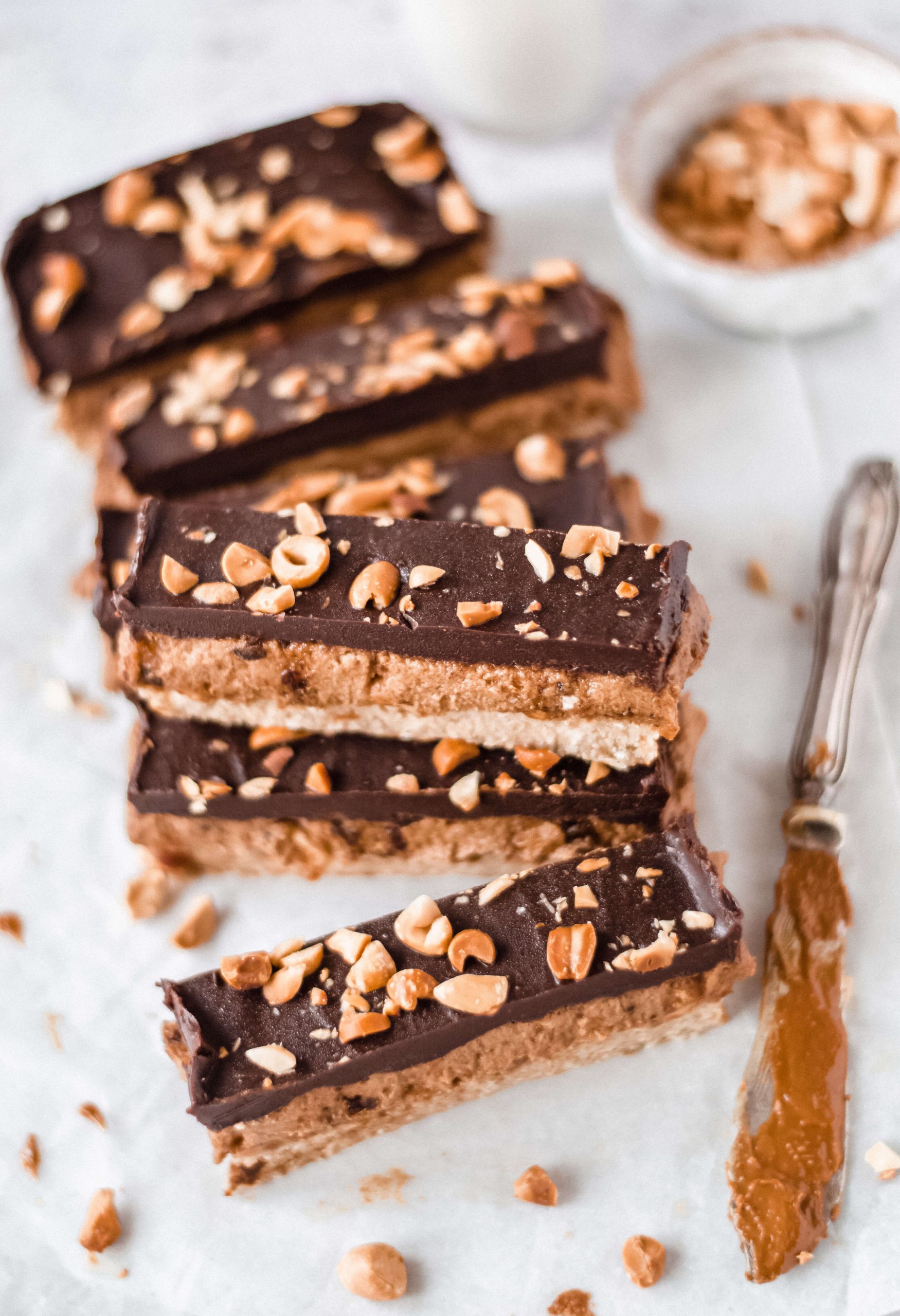 Close up view of vegan peanut and caramel bars with nuts, knife on the side 
