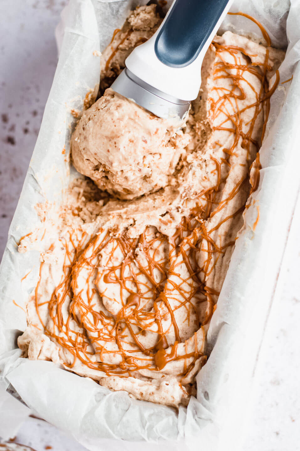 No-churn vegan Biscoff ice cream in container with ice cream scoop