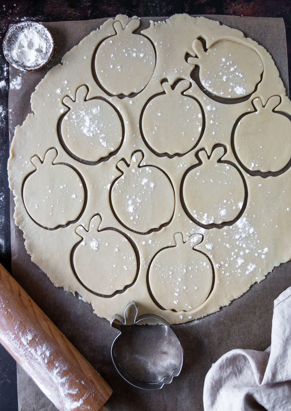 Top down view of pastry with cut out apple shapes & a rolling pin
