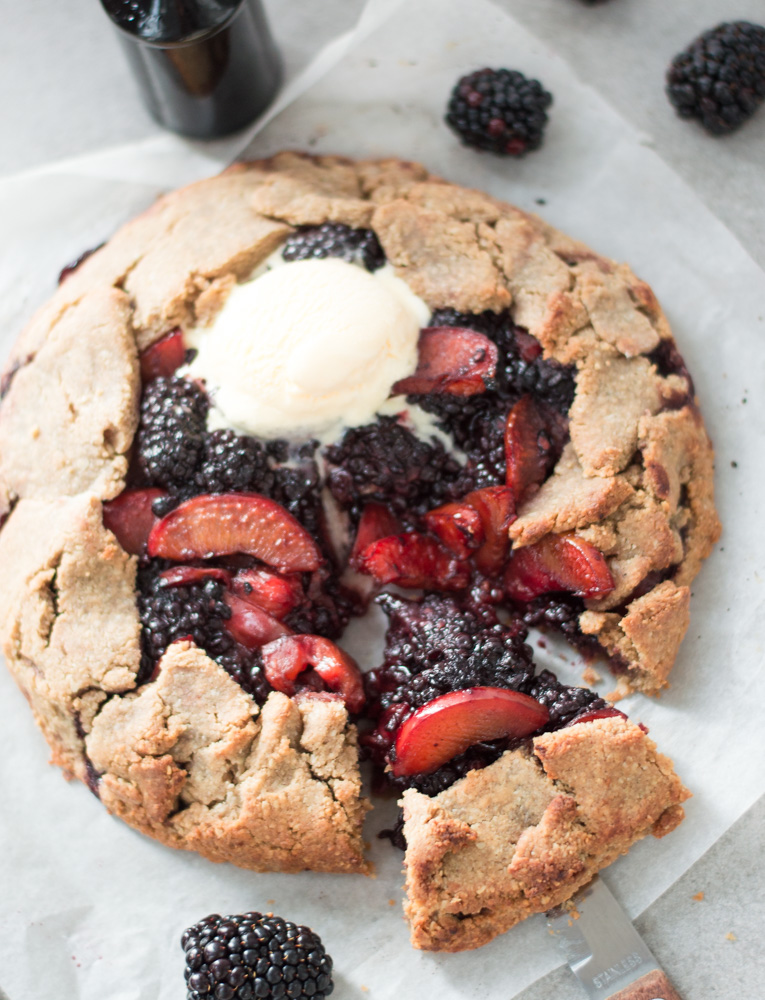 Top down view of freshly baked plum & blackberry galette with a scoop of ice cream