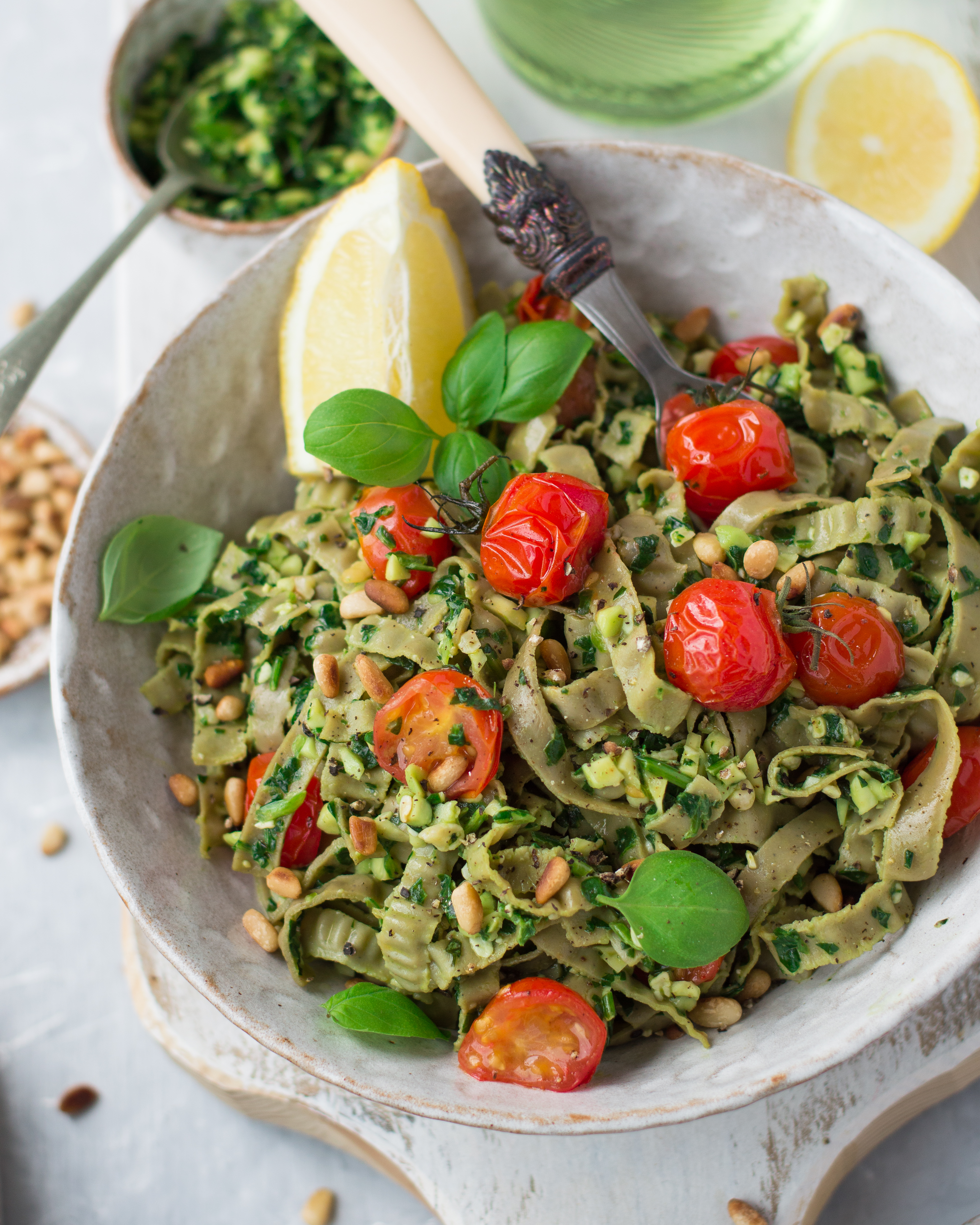A bowl of pasta with cherry tomatoes, basil & lemon, fork inside the bowl