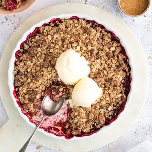 Raspberry & Rhubarb Crisp with ice cream in a white pie dish