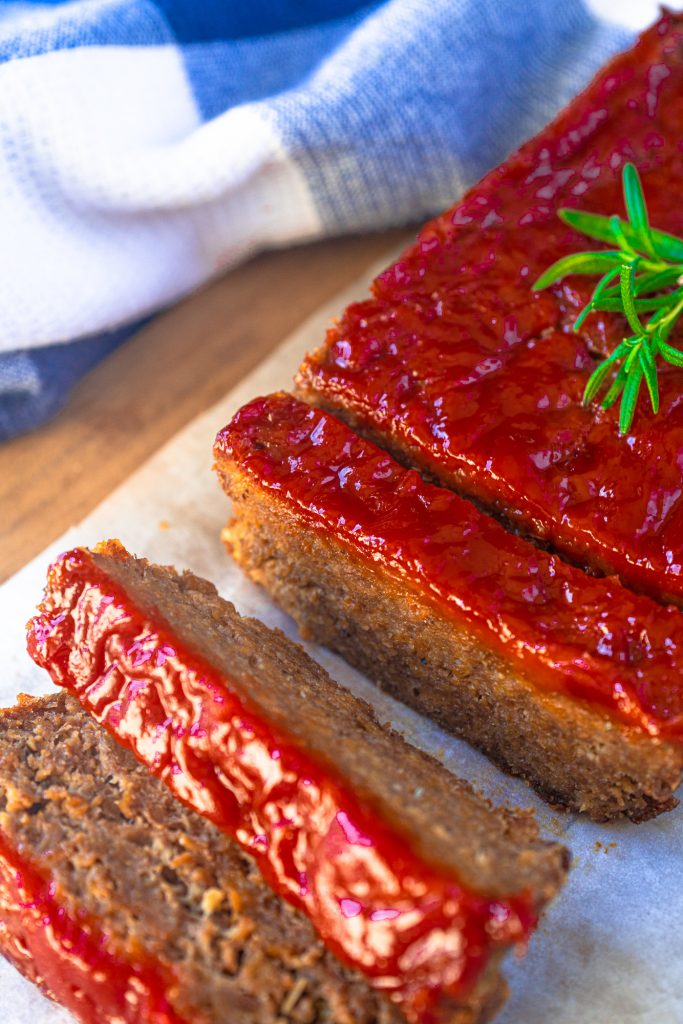 45 degree of vegan meatloaf topped with red ketchup glaze, 3 pieces cut