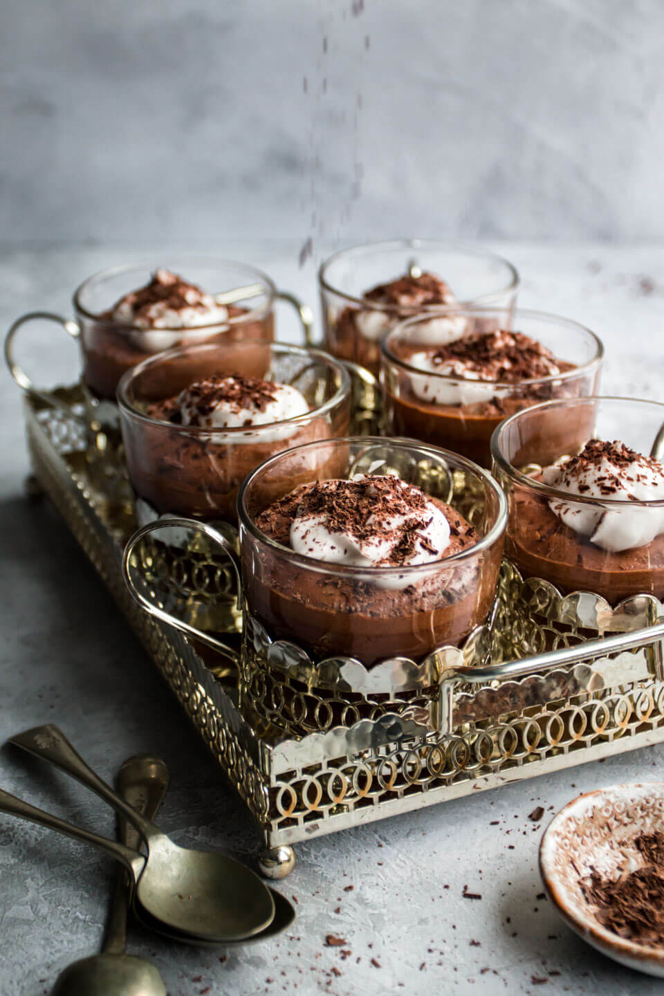 vegan chocolate mousse in small glasses in a silver tray sprinkled with chocolate 