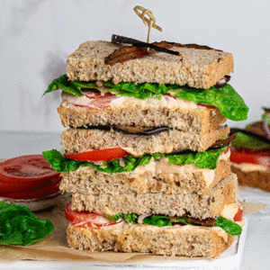 Vegan BLT sandwich with eggplant bacon on a white board