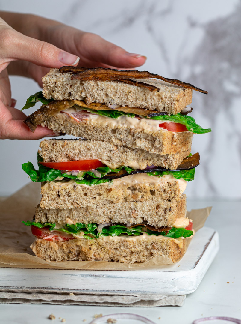 Hands holding a vegan BLT sandwich 