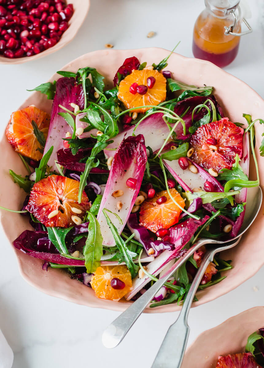 Close up view of chicory salad with rocket & blood oranges in a pink bowl 