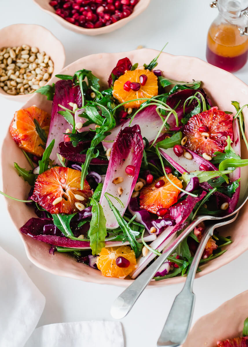Close up view of chicory salad with rocket & blood oranges in a pink bowl 