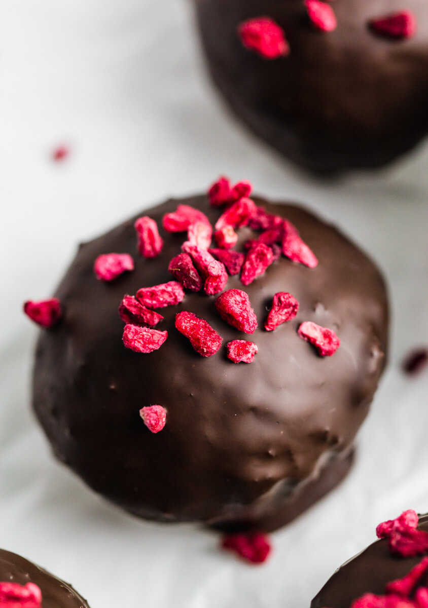 Close up view of chocolate date ball with freeze dried raspberries