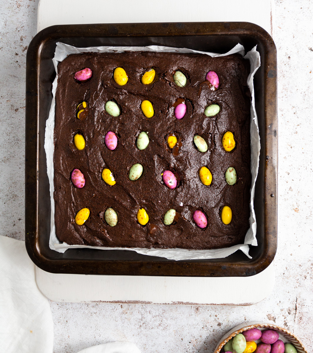 Top down view of vegan brownies in a pan with mini chocolate eggs 