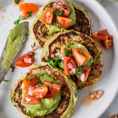 Top down view of savoury vegan pancakes topped with guacamole and tomato salsa
