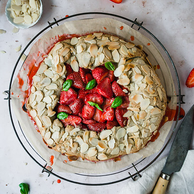Top down view of vegan strawberry tart with basil leaves