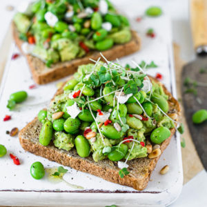 Vegan avocado toast with edamame beans & feta on a white board