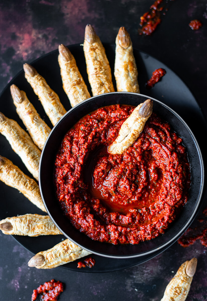  Witches’ finger breadsticks on a black plate with red pepper dip 