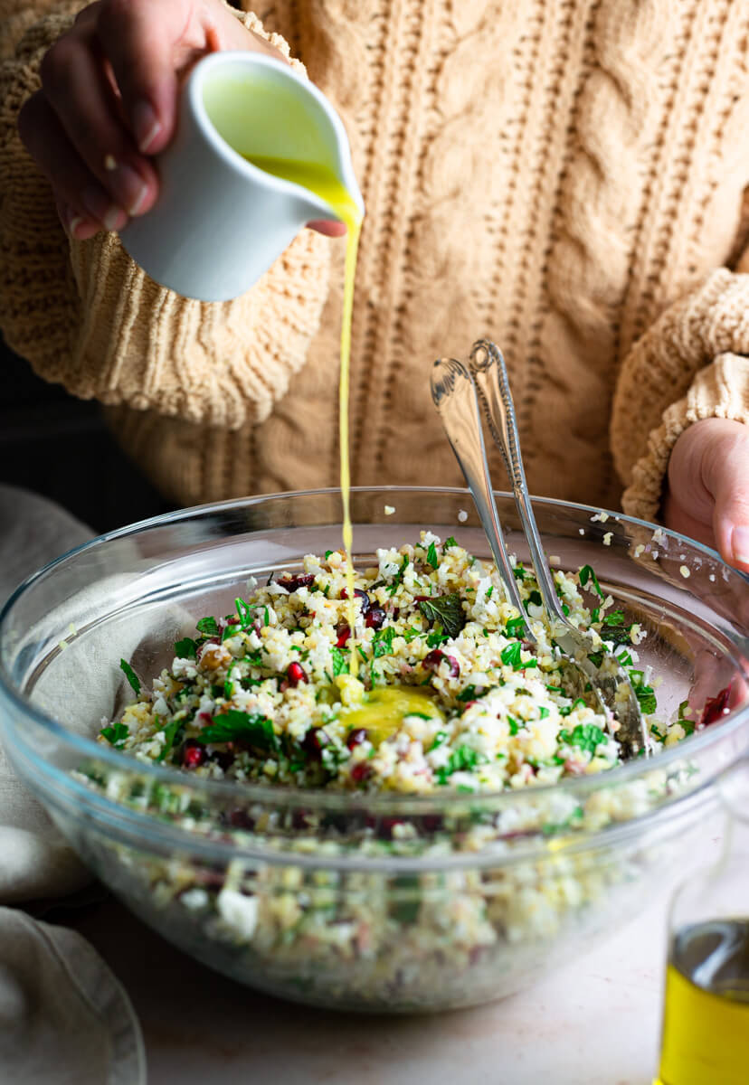 Pouring dressing over winter tabbouleh salad