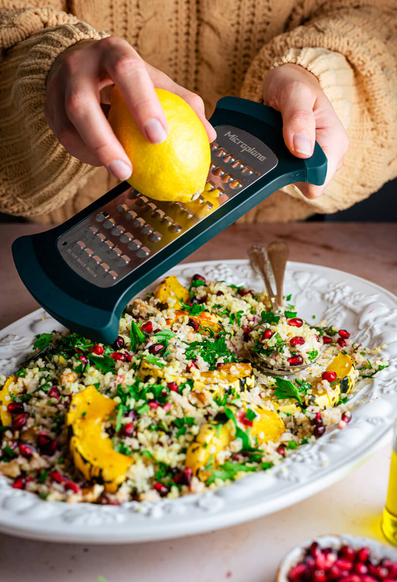 Grating lemon zest over winter tabbouleh salad