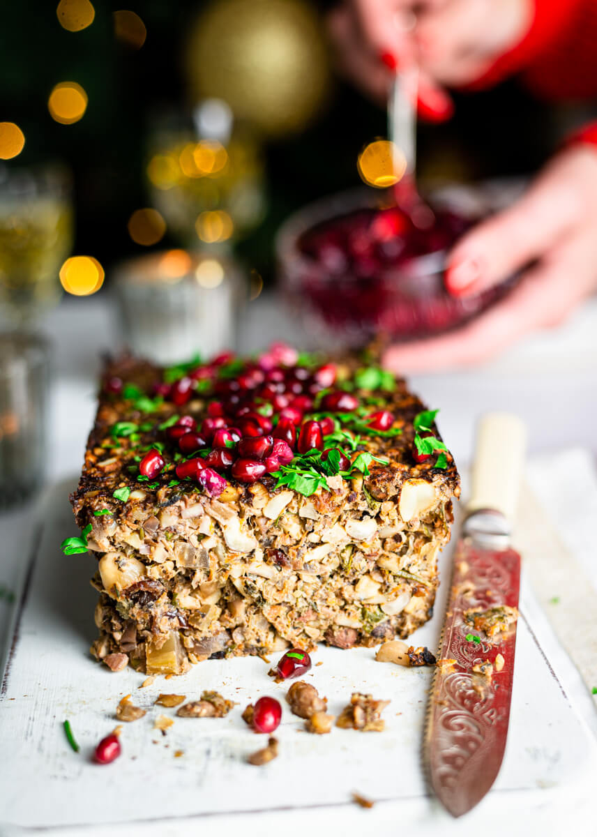 Vegan nut roast on a white board with pomegranate seeds